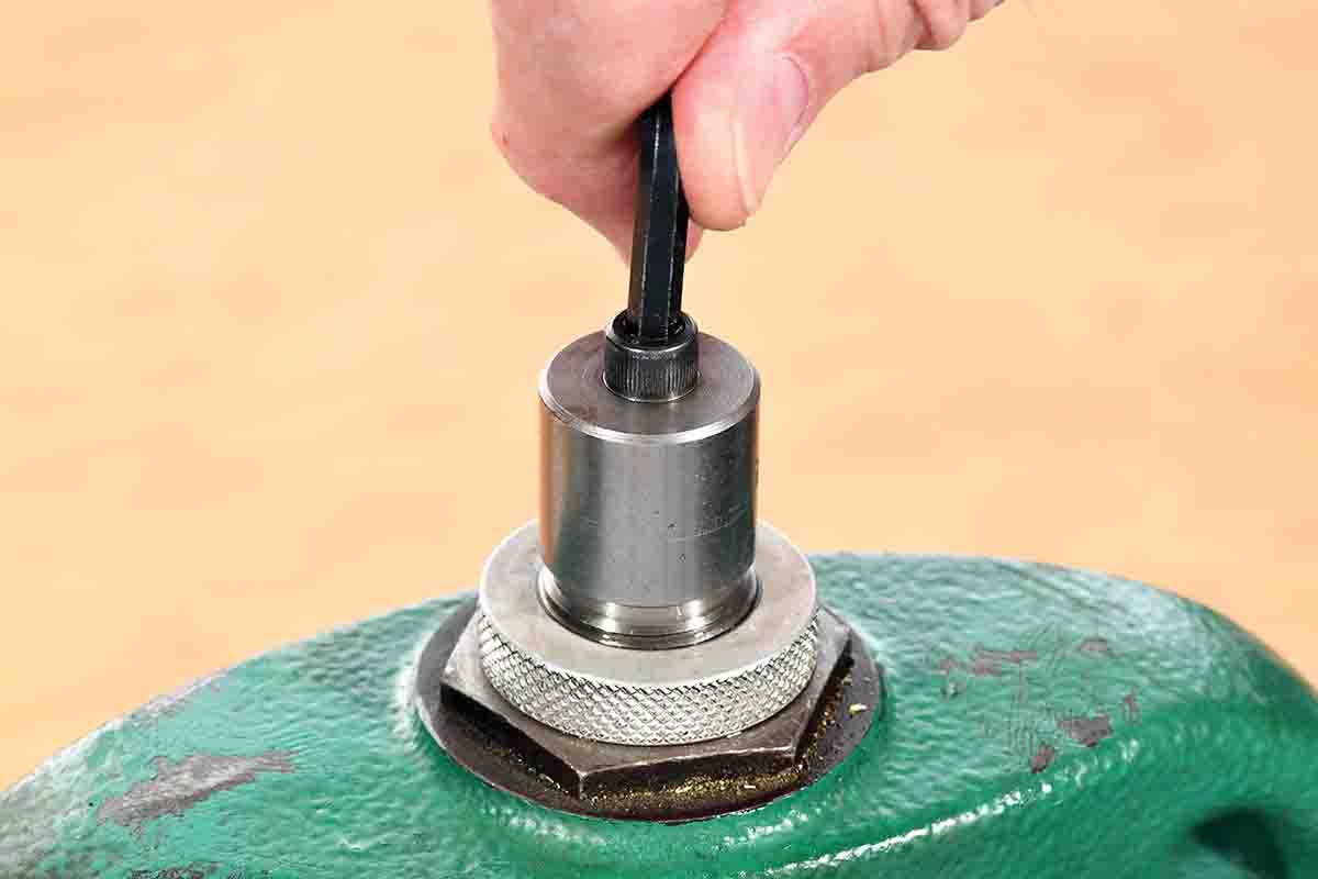 A hex wrench is used to turn the hex head cap screw to extract the case from the die.